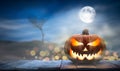 One spooky halloween pumpkin, Jack O Lantern, with an evil face and eyes on a wooden bench. Royalty Free Stock Photo