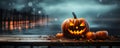 One spooky halloween pumpkin Jack O Lantern with an evil face and eyes on a wooden bench table with a misty gray coastal night Royalty Free Stock Photo