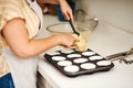 One spoonful is more than enough. an unrecognizable woman spooning batter into a muffin pan.