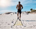 One sporty athletic african american man using an agility ladder during his training in the sand at the beach a sunny Royalty Free Stock Photo