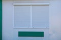 Square window closed by white roller shutters on a gray wall Royalty Free Stock Photo