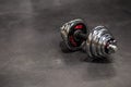 One steel chrome-plated collapsible dumbbells lie on the gray floor