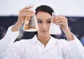 One step closer to a cure. a female scientist observing liquids in conical beakers.