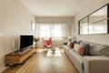 One-story living room furnished with gray three-seater sofa with mirror set, wooden sideboard with tv and window with views