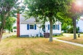 One story small residential home with board siding on the facade. With a large lawn and a tree