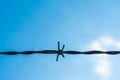 One strand of barbed wire with blue sky and clouds in the background Royalty Free Stock Photo