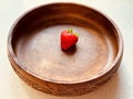 One strawberry in a circular wooden bowl. Royalty Free Stock Photo