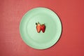 One strawberry cut in half on green plate. Two strawberry halves Royalty Free Stock Photo