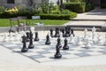 One street chessboard with black and white chessmen, chairs and green plants in the daylight