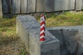 One striped iron pole limiter with a reflector on a gray concrete block Royalty Free Stock Photo
