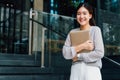 One successful and happy young adult business woman holding a laptop with smile. Professional female worker standing in Royalty Free Stock Photo