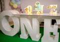 One table and the party decorations for the celebration of the baby girl`s 1st birthday. Pastel-colored balloons in the backgroun Royalty Free Stock Photo