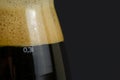 One tall glass of cold dark craft beer over black background. Close up. Copy space