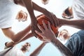 One team, one dream. Closeup shot of a group of sporty young men huddled around a basketball on a sports court.