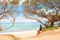 One teen girl sitting alone on beach under trees Royalty Free Stock Photo