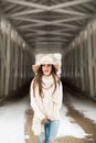 One teenage high school senior portrait wearing floppy hat at covered bridge in winter