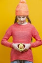 Human Health Concepts. Teenager Girl In Coral Knitted Clothing With Split Avocado Fruit In Front of Belly as a Demonstration of