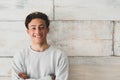 One teenager at home smiling happy at the camera - simple photo of handsome young man looking with wooden wall at the background