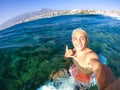 One teenager man enjoying surfing lifestyle at the beach in the sea or ocean - happy and handsome millennial smiling and looking Royalty Free Stock Photo