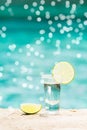 Tequila shot with lime on blue background with gentle festive holiday bokeh