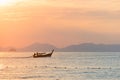 Thai long-tailed traditional boat floats on a beautiful colored sunset on the sea against the silhouette of the mountains in Royalty Free Stock Photo