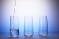 One-third full, two empty drinking glasses. Water pouring Royalty Free Stock Photo