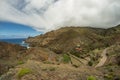 One of the tight turns of a narrow rural road in the mountains of Parque Natural Majona. View of Playa De Caleta the north-eastern