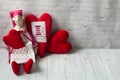 One tilde doll in a red dress, and a white apron, and in a red kalpak sits on a light background with red textile hearts