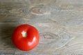 One tomato red, close-up isolated on a wooden brown background. Royalty Free Stock Photo