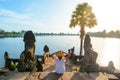 One tourist relaxing in Angkor ruins at sunrise, Srah Srang temple water pond amid jungle, travel destination Cambodia. Woman with Royalty Free Stock Photo