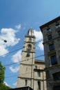 One tower of GrossmÃÂ¼nster Churs in Zurich with the corner of a neighboring historical buildingwith the blue sky and a white cloud