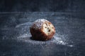 A single traditional Dutch oliebol (dough fritter) on a textured black background horizontal