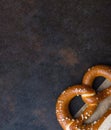 One Traditional German Savory Lye Pretzel with Salt on Piece of Parchment Paper on Dark Rustic Rusty Background