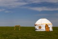 Russia. One traditional Kalmyk or Mongol yurts with washbasins and garbage cans in a green spring steppe under the blue sky