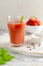 One transparent glass cup with red tomato juice and a sprig of celery on a light background. Healthy food concept. Royalty Free Stock Photo