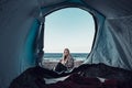 One traveler viewed from inside a tent in free beach camping lifestyle. Concept of solo woman in travel. Freedom and alternative Royalty Free Stock Photo