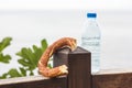 One Turkish bagel simit and watter bottle laid on a wooden surface, close-up