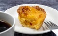 One uneaten Pastel de nata or Portuguese egg dessert on a white plate. Pastel de Belm is a small pie with a crispy puff
