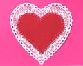 One Valentines Day Heart made of a white doilie with a red stitched, handmade felt heart, all on a bright pink paper with space in Royalty Free Stock Photo