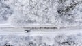 One vehicle driving through the winter snowy forest on country road. Top view