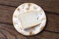 One water biscuit with cheese, on wood from above.