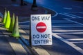 A ONE WAY DO NOT ENTER sign on a street with a red circle with a white like through it in the center of the sign with yellow cones Royalty Free Stock Photo