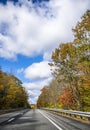 One-way highway road with yellowed autumn maple trees on the sides in New England Royalty Free Stock Photo