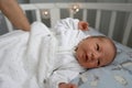 One week newborn adorable baby lying at baycot and funny yawning.Portrait of sleepy caucasian infant tired child on bed