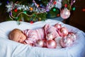 One week old newborn baby girl with pink balls near Christmas tree Royalty Free Stock Photo