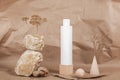 One white blank cosmetic tube with cream, lotion or shampoo, stones, geometric shape, dried plant flowers on beige craft paper Royalty Free Stock Photo