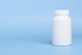 One white blank plastic medical pill or supplement bottle on blue background Royalty Free Stock Photo