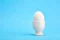 One white egg in an egg cup on blue background Royalty Free Stock Photo