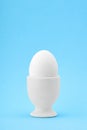 One white egg in an egg cup on blue background Royalty Free Stock Photo