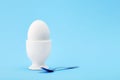 One white egg in an egg cup on blue background Royalty Free Stock Photo